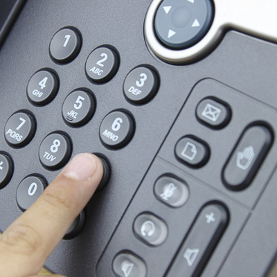 Person dialling a number on a business phone keypad.