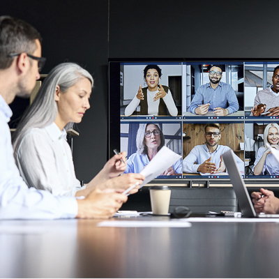 Remote video conferencing business meeting. Executives sit in a boardroom and video call with other team members.