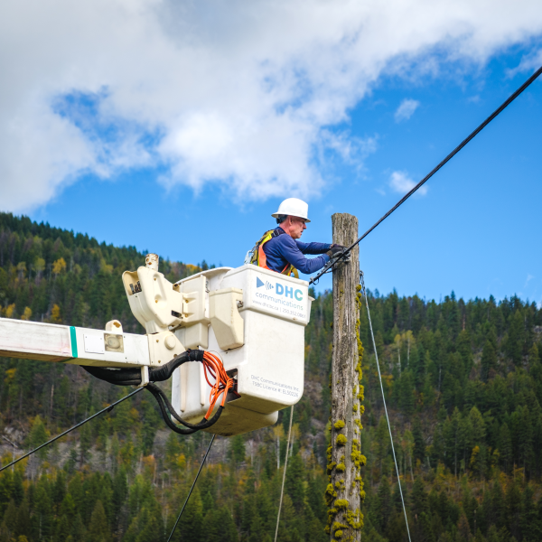 DHC Technician in a bucket hoist crane installing outdoor Fibre Optic infrastructure in a rural area near salmo bc, as part of the CBBC Nelson-Fruitvale Fibre Infrastructure project